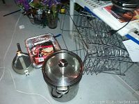 Steamer pot with lid, perforated insert, and aluminum pans partially visible.