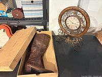 Boots in box next to decorative table clock