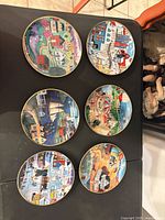 All six decorative plates showing varied folk-art scenes and gold rims