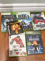 Group shot of six Xbox game cases and disc