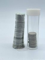 Shrink-wrapped roll beside plastic coin tube containing quarters