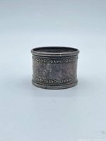 Front view of sterling napkin ring showing engraved 62 and floral borders