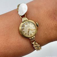 Watch on wrist showing size, gold-tone case, aged dial, stretch band