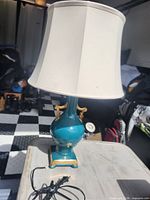 Front view of teal ceramic lamp with shade and cord