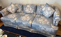Full view of floral three-seat sofa with pillows