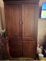 Front view of solid wood armoire showing double doors, two small upper drawers, lower cabinet doors, cherry finish
