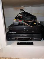 Stacked Apex AD-1200 DVD player and Quasar VCR with remote and cable bundle