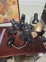Group of lamps lying on desk showing cords, bases, mixed finishes