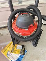 Front view of RIDGID shop vacuum with hose, nozzle and filter bag pack