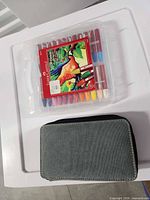 Plastic case of Faber-Castell oil pastels beside closed grey carry case