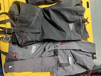 Black and grey REI gaiters laid flat showing full length, closures, straps, logos