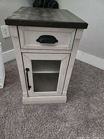 Front view of side table showing drawer and glass door