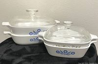 Four Corning Ware dishes stacked in two pattern groups with lids