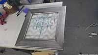 Grey square frame with chandelier print on workbench