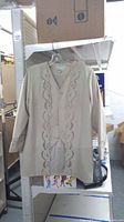 Front view of beige embellished jacket on hanger