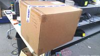Full view of sealed brown shipping carton on shelf