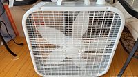 Front view of white Lasko box fan showing blades and grille