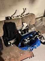 Lot overview showing white figure skates on cushion, goggles, plastic bin with skates, tote with hockey skates