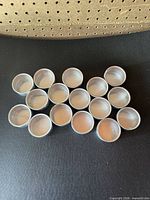 group of small aluminum tins with lids displayed on black surface