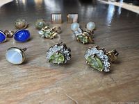 Close view showing peridot halo pair foreground; additional gemstone studs in background