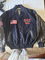Front view of varsity jacket showing patches, leather sleeves, snap front