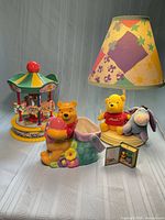 Full lot showing carousel music box, ceramic planter, lamp with shade and plush, mini book ornament