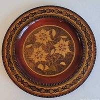 front view of carved wooden plate showing floral design and border
