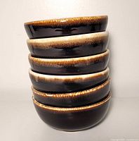 Stacked view of six matching brown drip glaze bowls