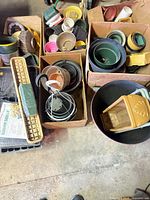 Overview of boxes filled with assorted pots, saucers, hooks, foam, trays