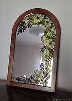Front view of arched wooden framed mirror showing painted floral design
