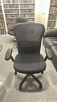 Front view of black mesh office chair showing seat, armrests, base
