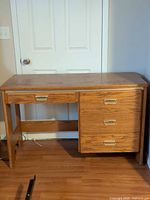 Full view of wood desk against wall showing right pedestal drawers and center drawer