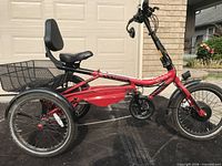 Left side view of red Trivel Azteca electric tricycle showing frame, seat with backrest, rear basket and front hub motor