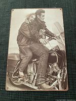 Front view of metal sign showing biker couple artwork and mounting holes