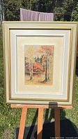 Full view of framed watercolor on easel outdoors