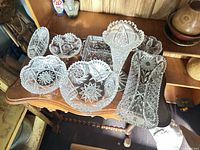 Group shot of all eight clear cut glass pieces on wooden table