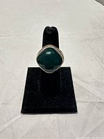 Ring on display stand showing front view with faceted green stone