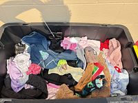 Overview of tote containing mixed infant and toddler clothing, denim, boots visible