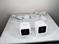 Front view of both Roku Indoor Camera SE units on bases with cables attached