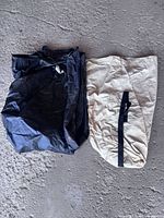 Black nylon storage bag beside beige canvas sack with black strap