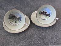 Two Royal Grafton teacups nestled in saucers showing interior Toronto landmark scenes, pale green and cream bodies with gold trim