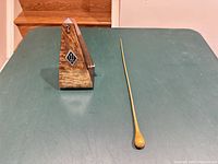 Closed wood metronome showing logo and separate wooden baton