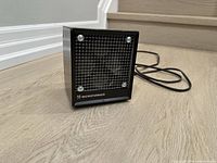Front view showing grille, fan blades, brand name and power cord