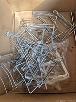 Box containing pile of silver wire display easels and some white pieces