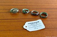 Four bronze rings and identification tag on wood surface