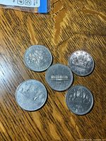 Group shot of five Canadian dollar coins showing designs and relative condition