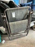 Folded zero-gravity chair showing frame, fabric sling and arm scuffs