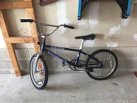 Full side view of the bike showing frame, seat, and tires against a wall