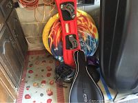 Image shows the snowboard, one helmet, the air disc sled and one tennis racket case on a floor mat near storage area