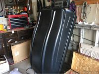 View of the full black rooftop carrier standing upright, showing shape and size in garage environment.